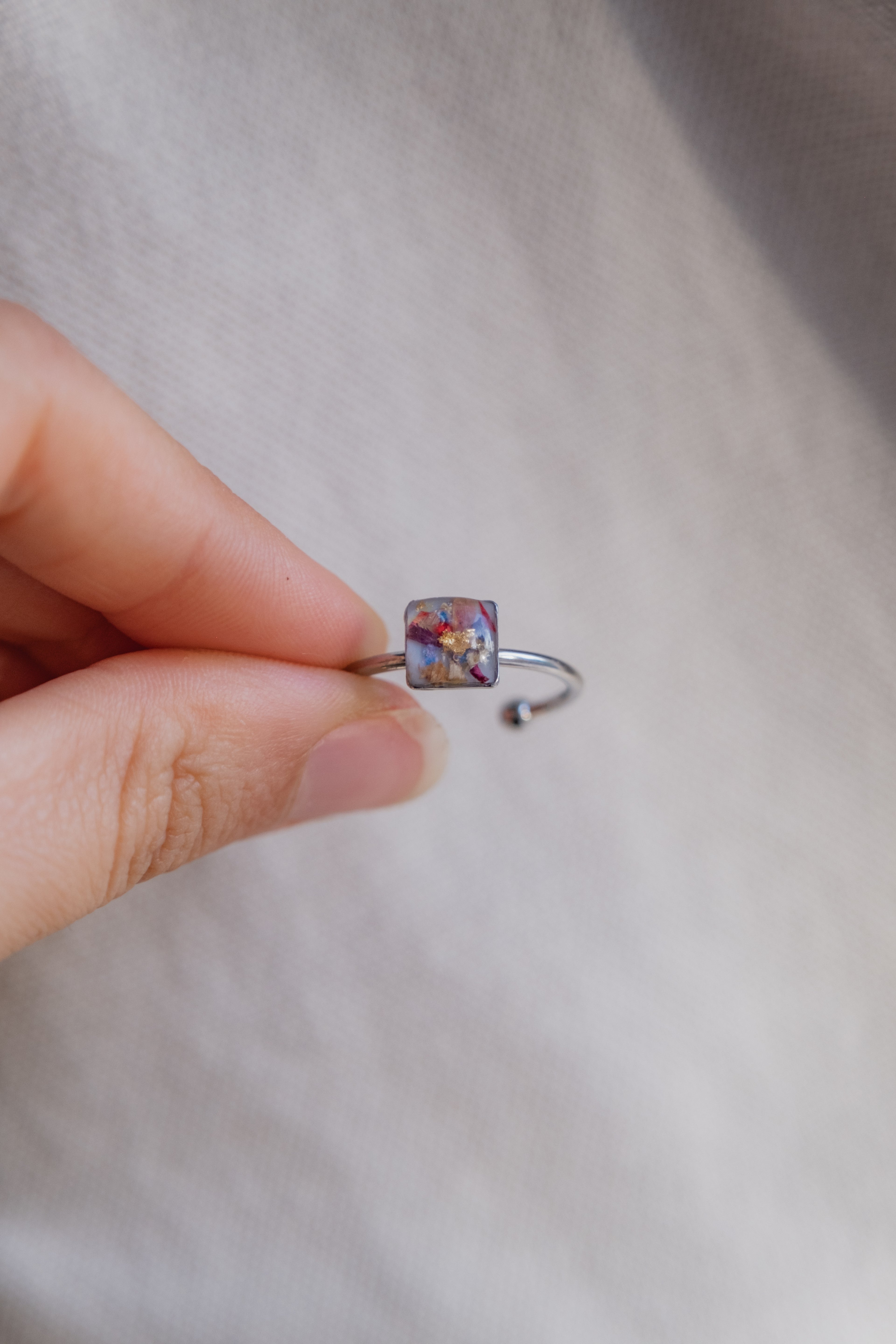 Anello con fondo bianco e frammenti di fiori e foglia oro