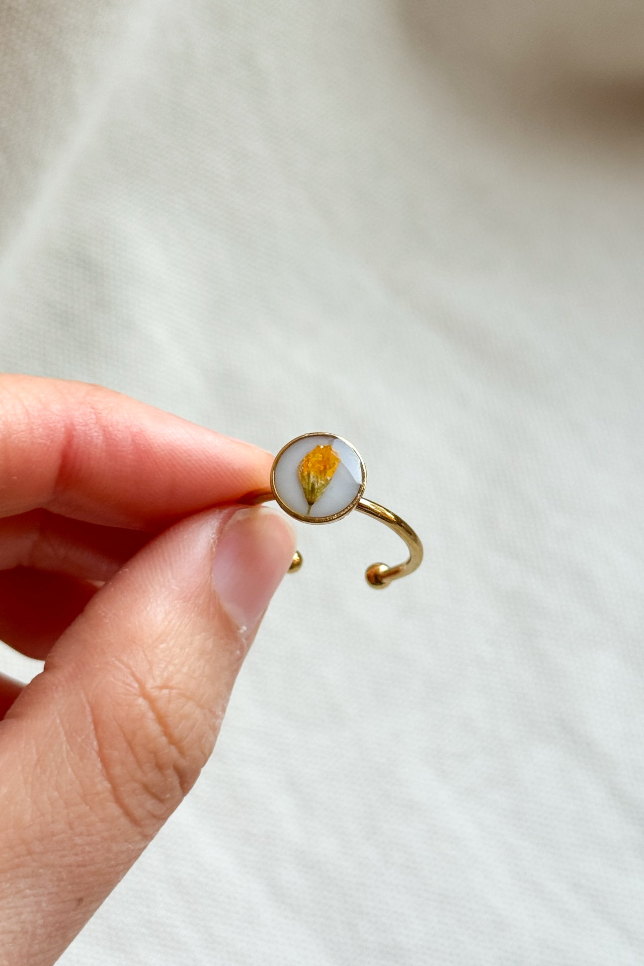 Anello con fondo bianco e fiori di campo gialli