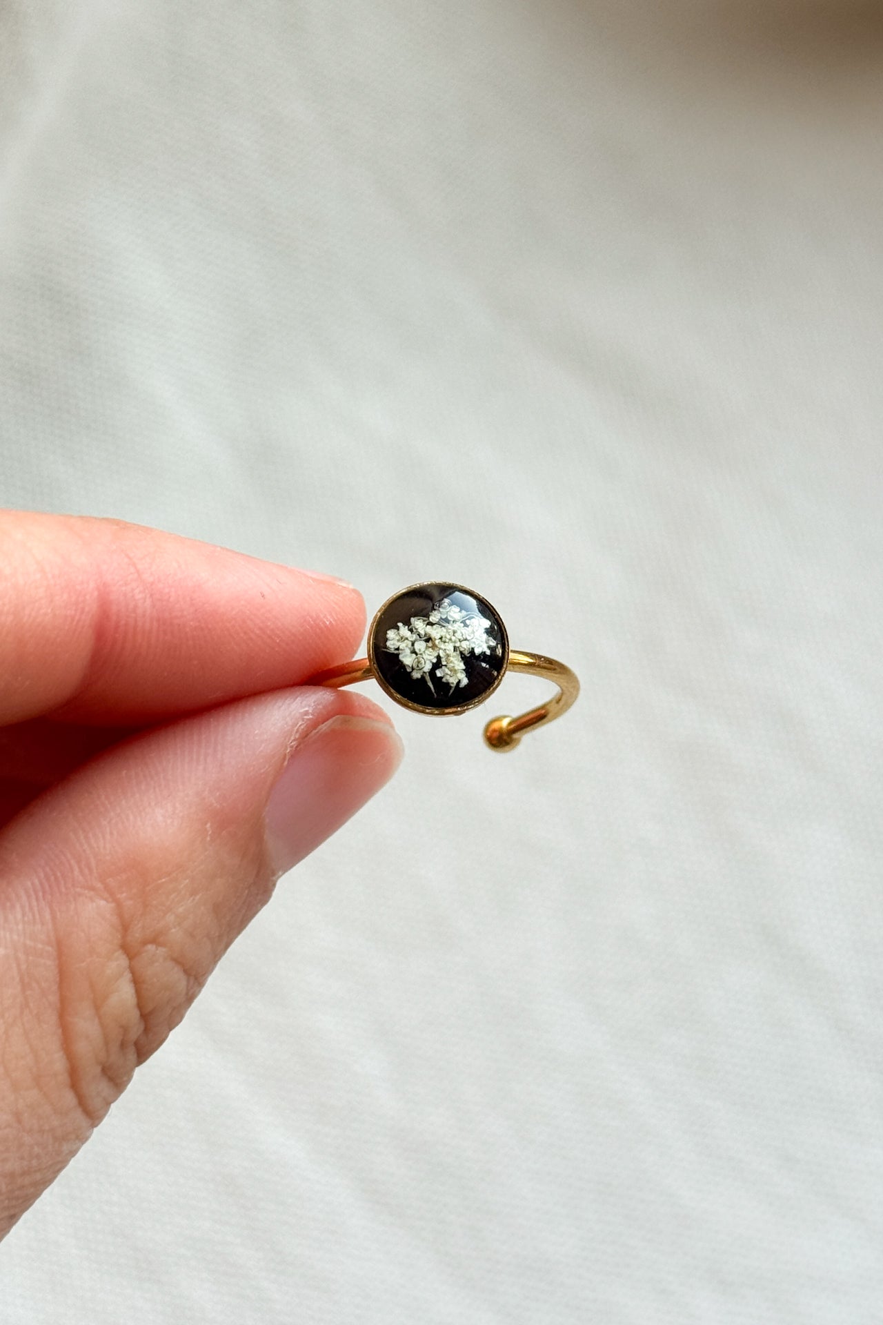 Anello con fondo nero e fiori di carota selvatica
