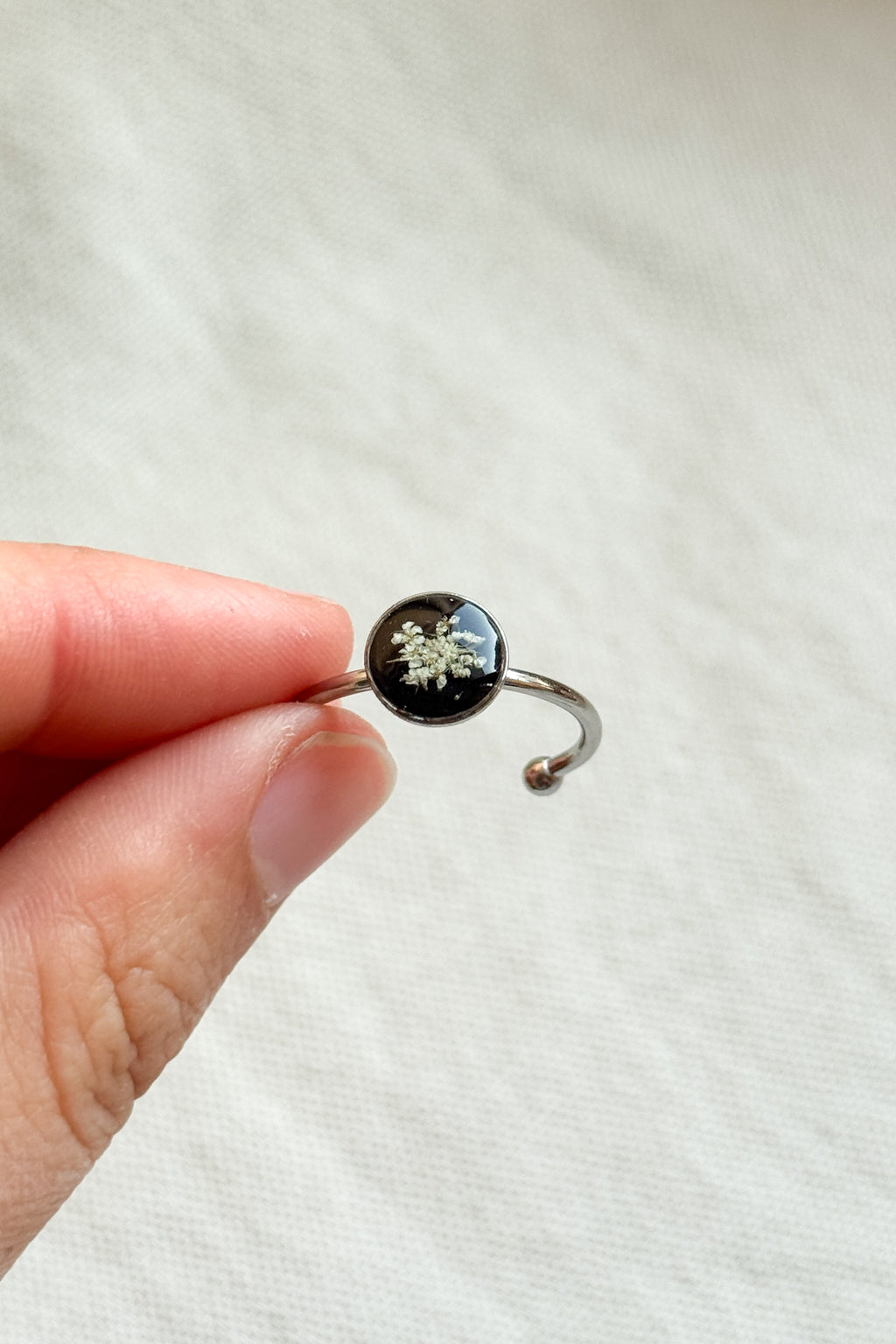 Anello con fondo nero e fiori di carota selvatica