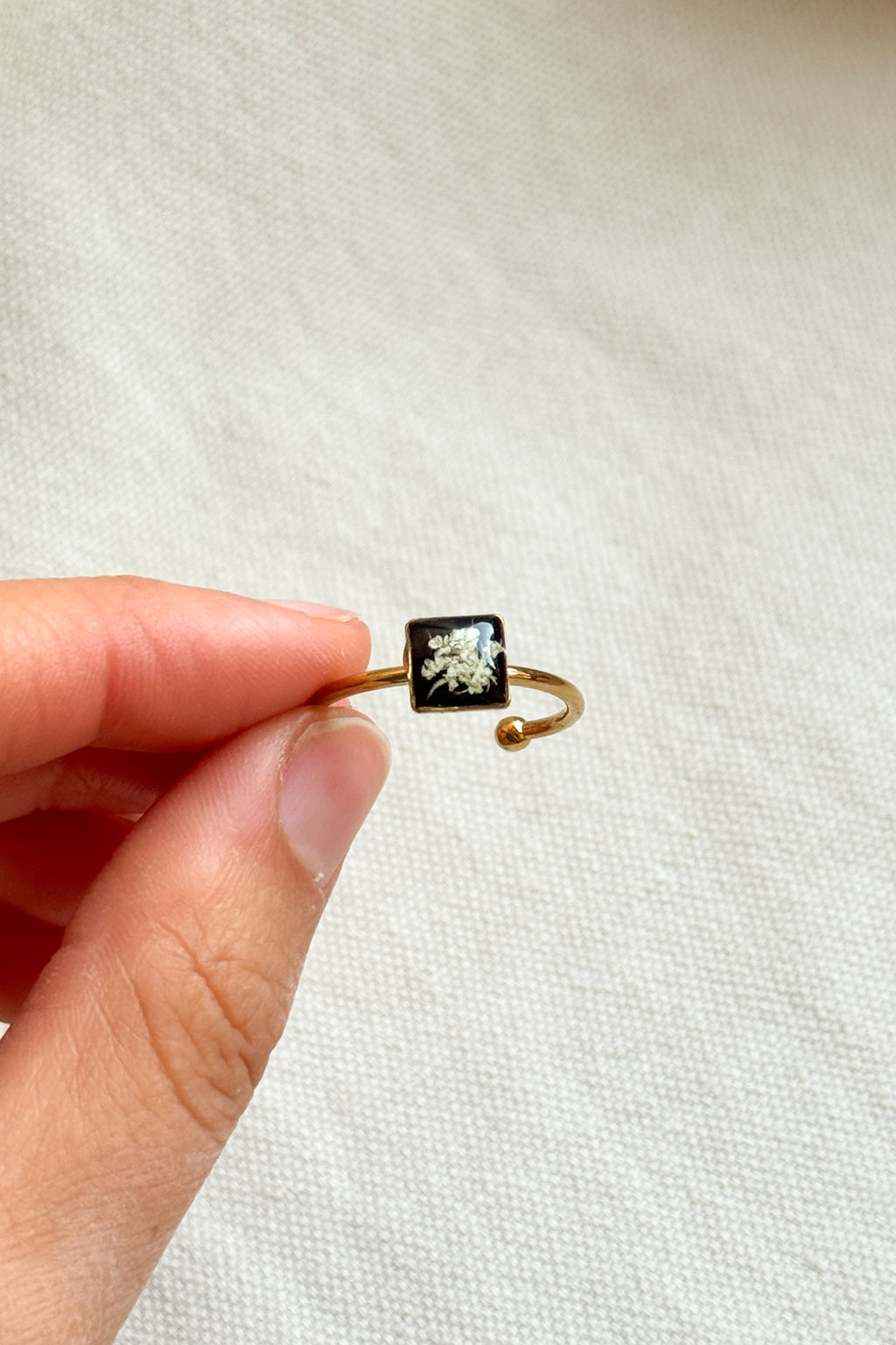 Anello con fondo nero e fiori di carota selvatica