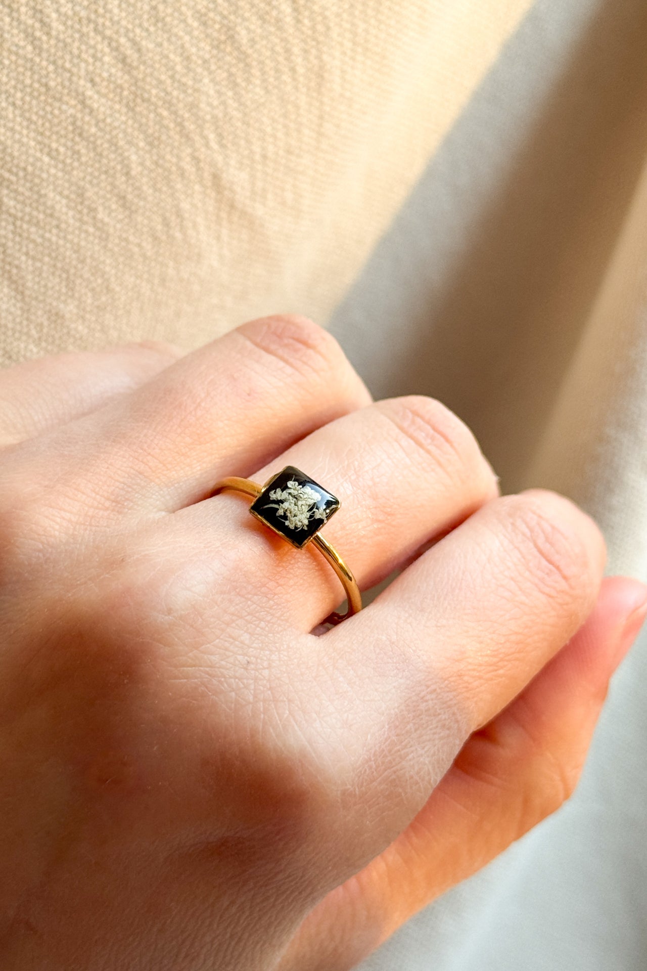 Anello con fondo nero e fiori di carota selvatica